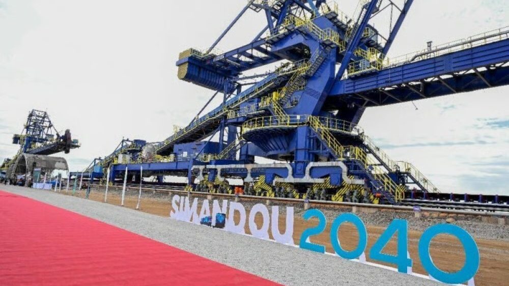 Gerbeur de minerai géant derrière les lettres Simandou 2040, lors de l'inauguration